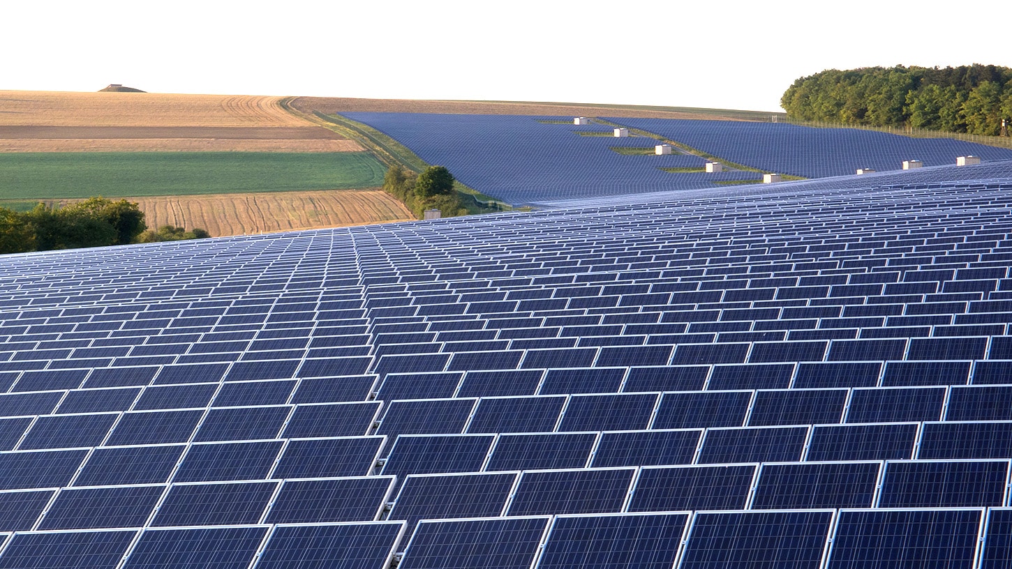 banks of solar PV panels in rolling countryside