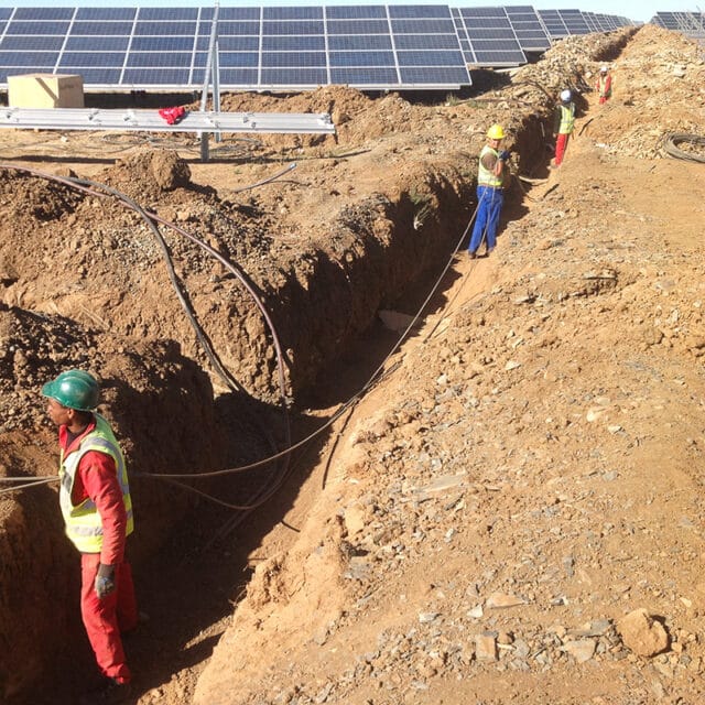 Construction workers lay cables from solar panels
