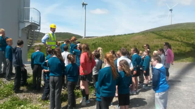 schoolchildren gather around Mainstream manager to learn about surrounding wind turbines