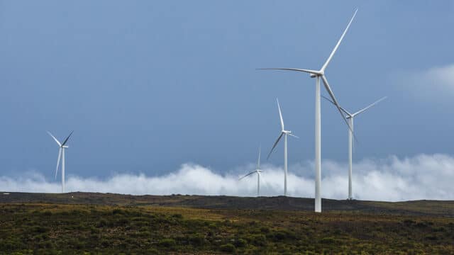 five wind turbines against blue cloudy sky