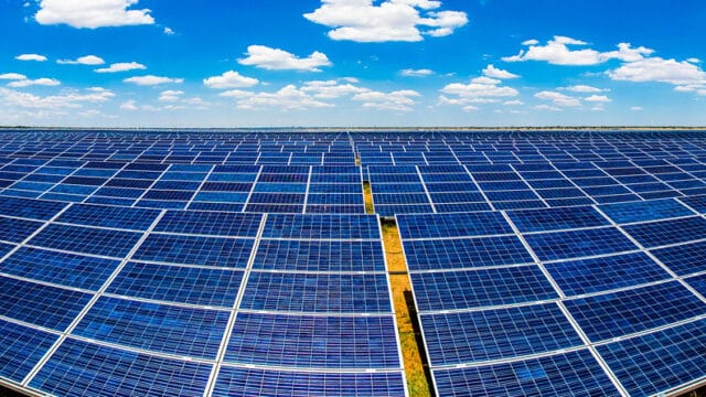 rows of solar pv panels under blue sky with clouds