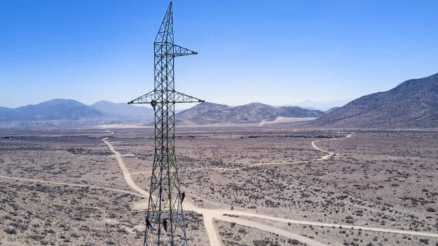 Aerial photo of construction workers installing transmission pylon in Chilean desert