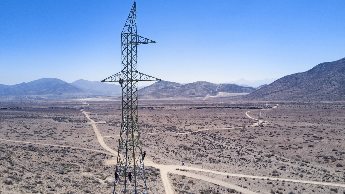 Aerial photo of construction workers installing transmission pylon in Chilean desert