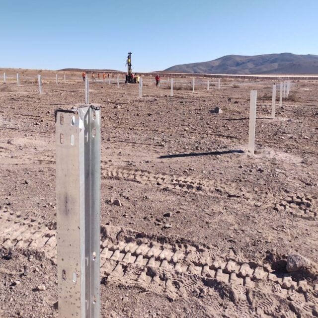 Close up picture of a solar pole in a dirt ground with blue sky in the background