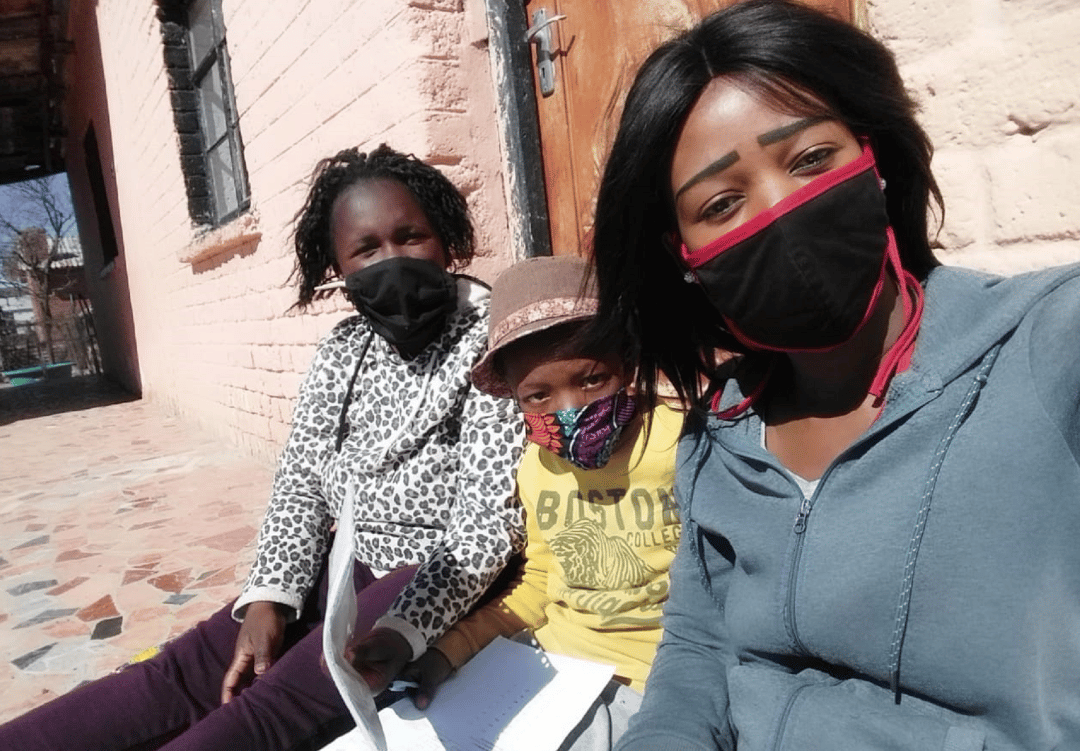 young boy sits between two female reading coaches, all wearing covid masks