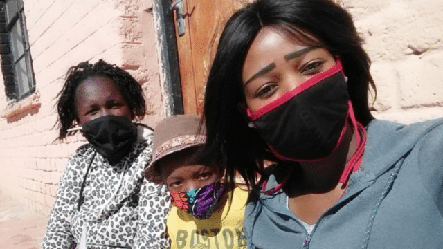 young boy sits between two female reading coaches, all wearing covid masks