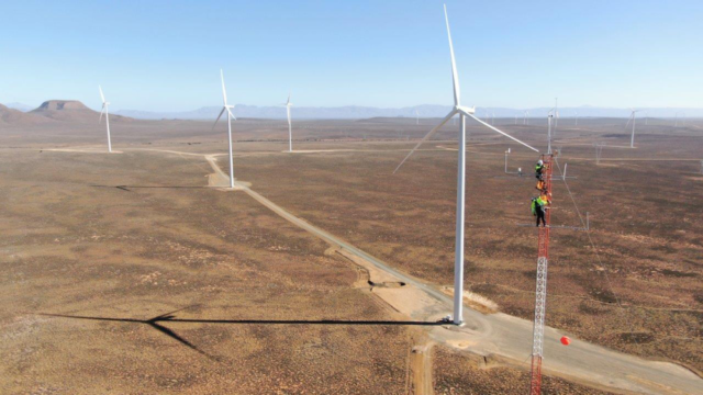 team members in harnesses climb a weather station radar at the Perdekraal East Wind farm