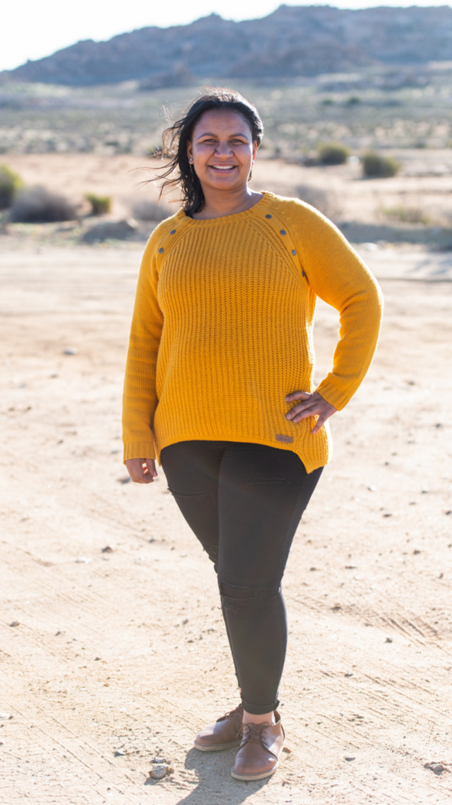 Leanne Schmidt standing in a yellow knit jumper, smiling