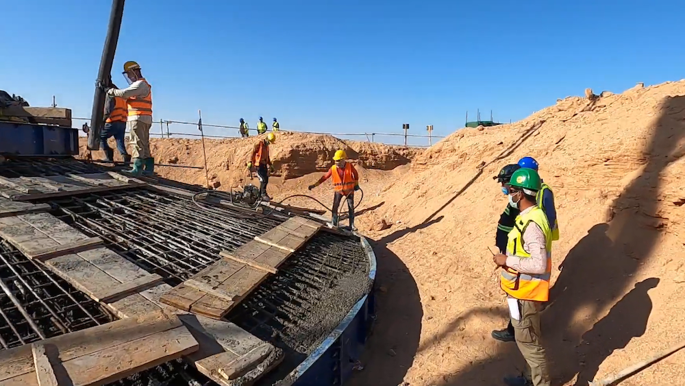 5 construction crew members pour cement on foundation on west bakr wind farm turbine foundations
