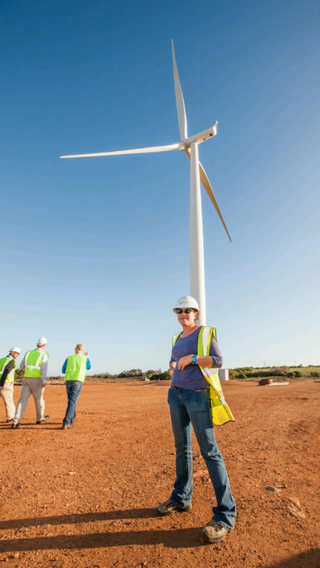 Leona Smith standing in front of a wind turbine