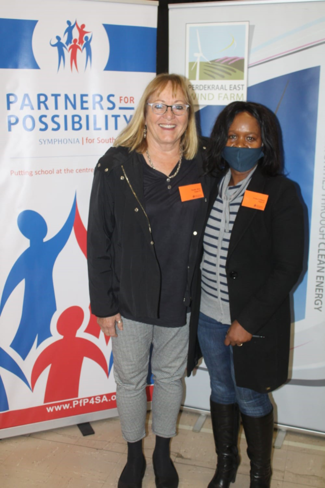 Two women, Dr Maddy Ross and Principal Fezeka Lethunya, standing smiling having their picture taken.
