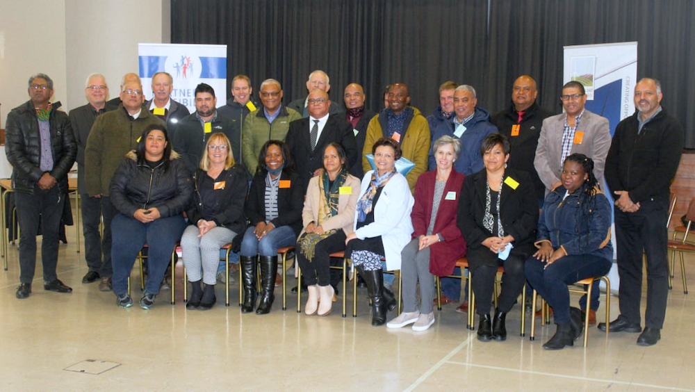 Group picture of school principals and their paired mentors. One row sitting in chairs, another row standing behind the seated.