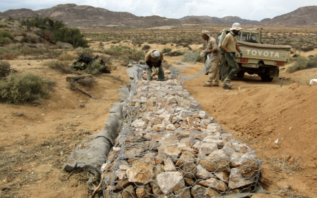 Park rangers building stone wall in reserve