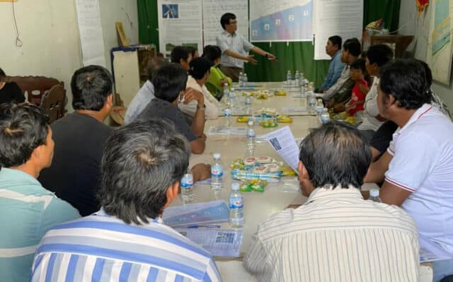 Mainstream team member gives presentation about Soc Trang project to local people seated at table