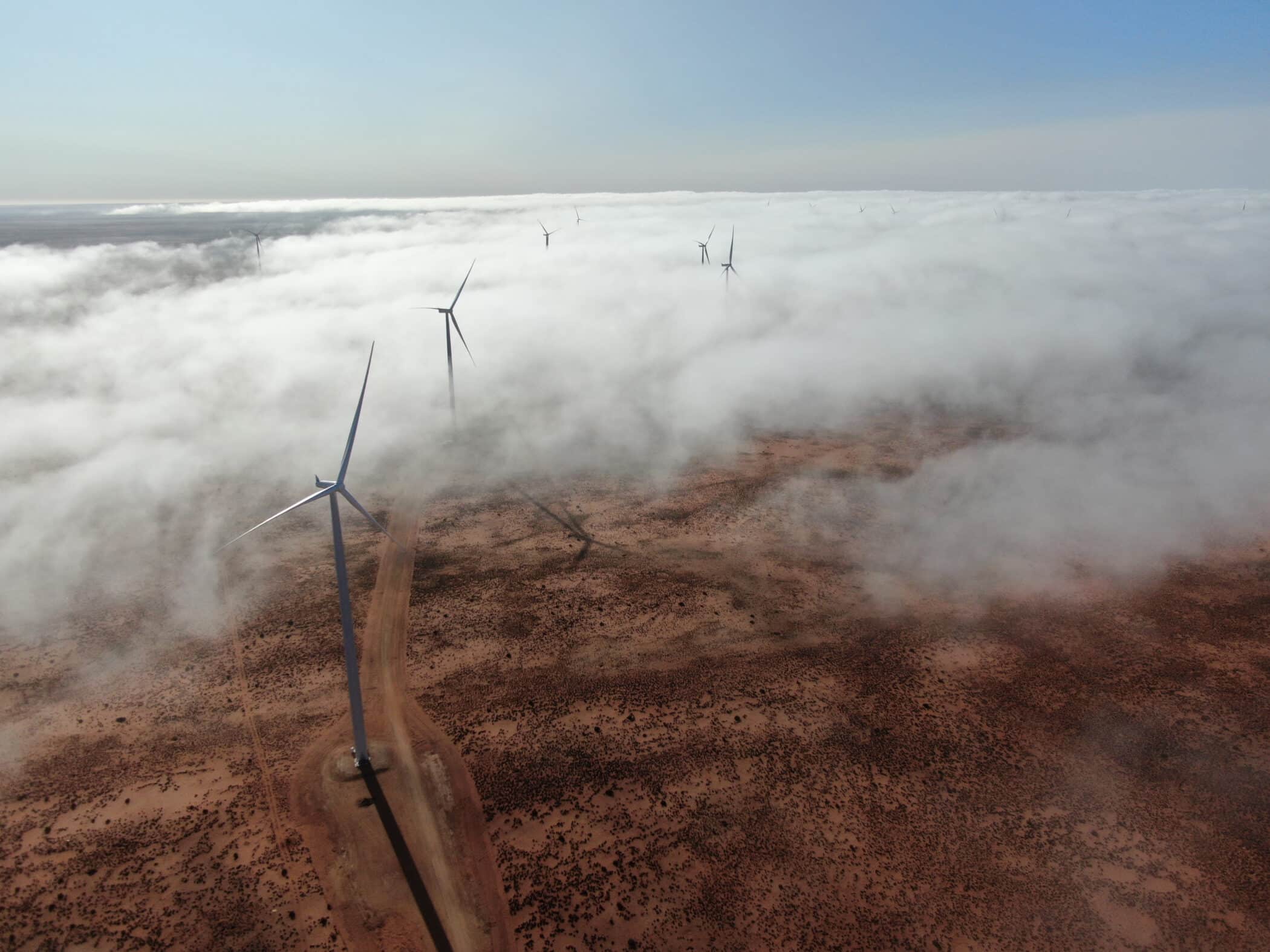 image of fog clouds covering south african desert plain with onshore wind turbines showing above the clouds