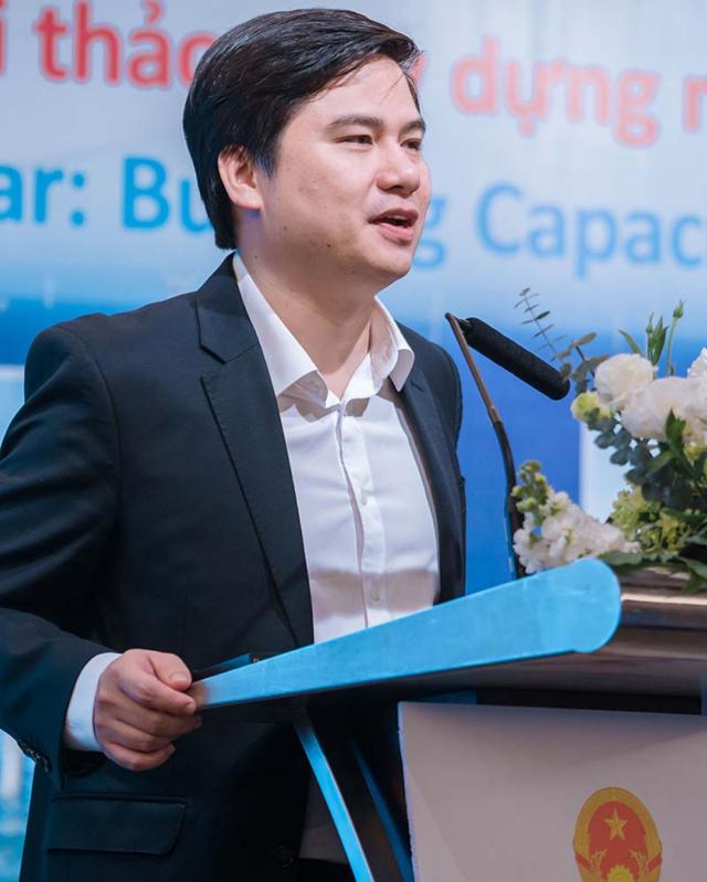 Deputy Director-General Nguyen Dong Trung standing at podium during speech