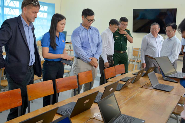 Mainstream's Bernard Casey hands over school parcels with Youth Assocation Secretary Trieu Thi Ngoc Diem, above, and is shown the refurbished laptops in action by Principal Trinh Quang Minh, below far right