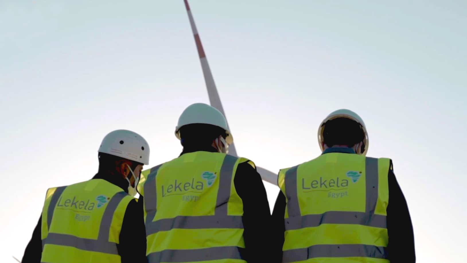 Three Lekel Power workers in hi-vis jackets and helmets on site of West Bakr Wind Farm