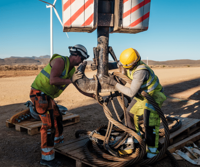 Construction members in PPE assisting the movement of heavy equipment - Planet Positive Impact - Mainstream Renewable Energy - Sustainability Report 2022