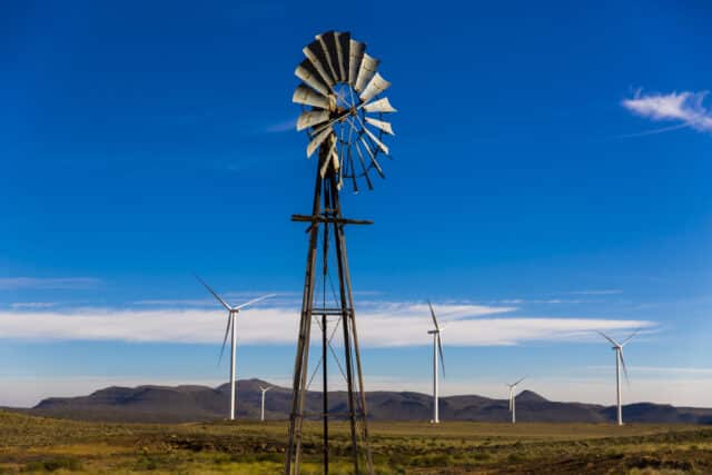 Wind turbines with an old windmill in foreground - Planet Positive Impact - Mainstream Renewable Energy - Sustainability Report 2022